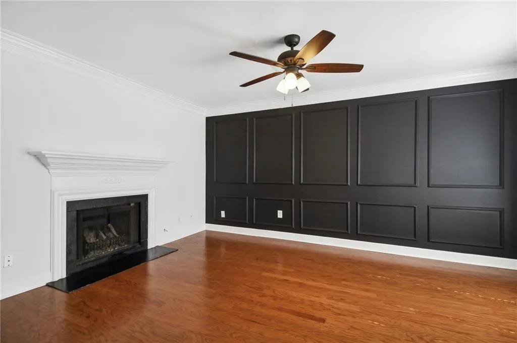 Lliving room featuring dark wood-type flooring, crown molding, and ceiling fan