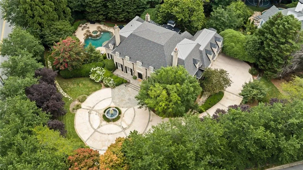A private gated estate surrounded by lush landscaping, featuring a grand circular motor court, elegant fountain, and resort-style pool