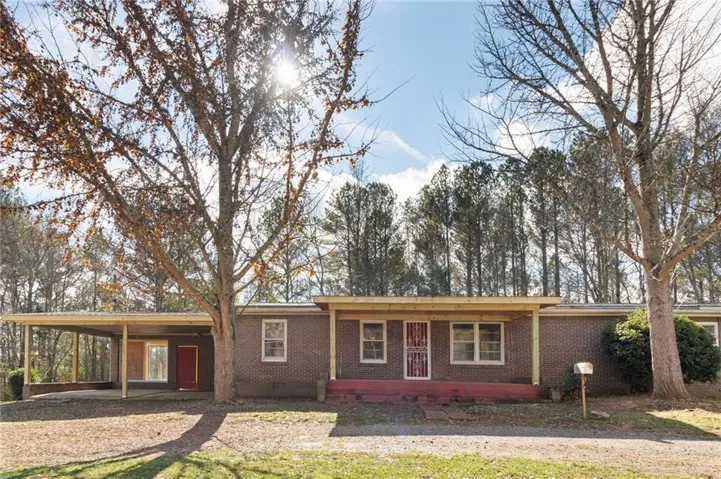 Ranch-style home featuring an attached carport, brick siding, and a porch