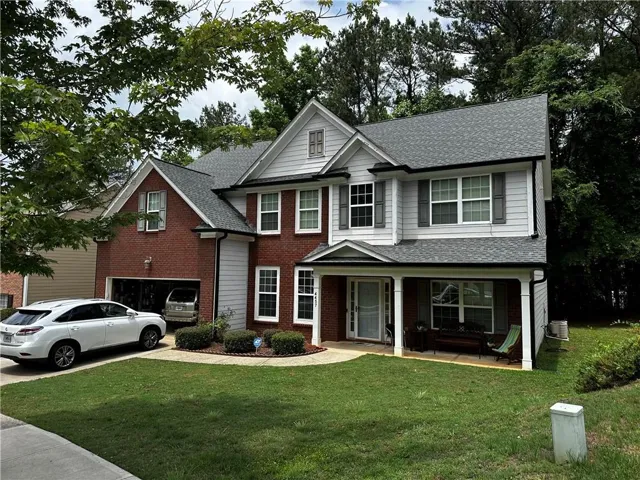 Traditional two-story home featuring a brick and siding exterior with a covered front porch