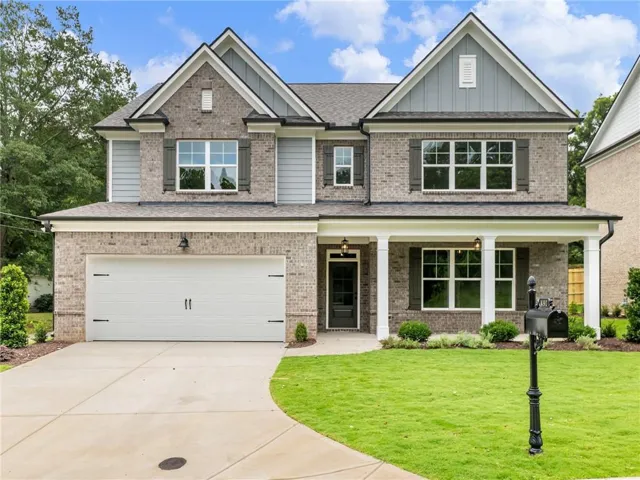Craftsman inspired home featuring an attached garage, board and batten siding, driveway, and a front lawn
