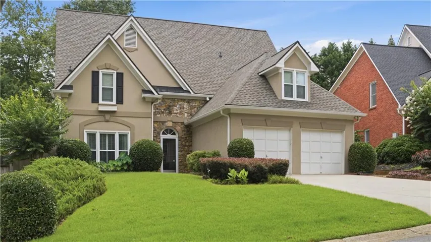 Hardcoat Stucco and stone facade featuring a prominent front gable, dual dormer windows, and an arched entry.