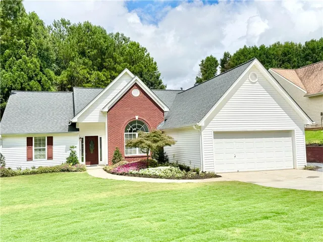 Ranch-style residence featuring white siding and a brick facade accent