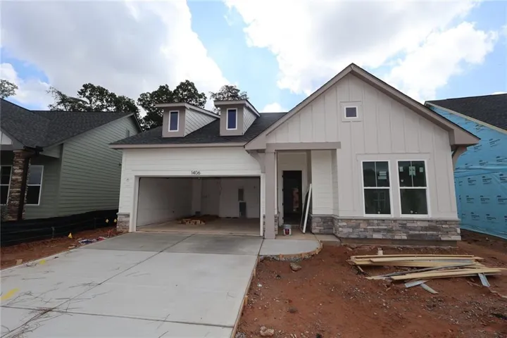 Modern farmhouse-style new construction featuring board and batten siding, stone veneer accents, a prominent front gable, a two-car garage, and dormer windows