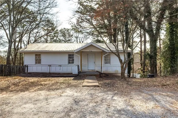 Ranch-style home with metal roof and fence