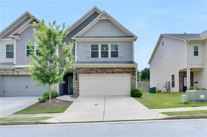 Two-story residence featuring a shake siding and brick facade, an attached garage, and a concrete driveway