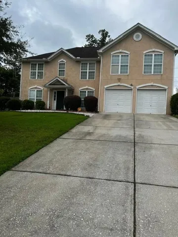 Two-story exterior, covered entry, dual garage doors, paved driveway, and established front landscaping