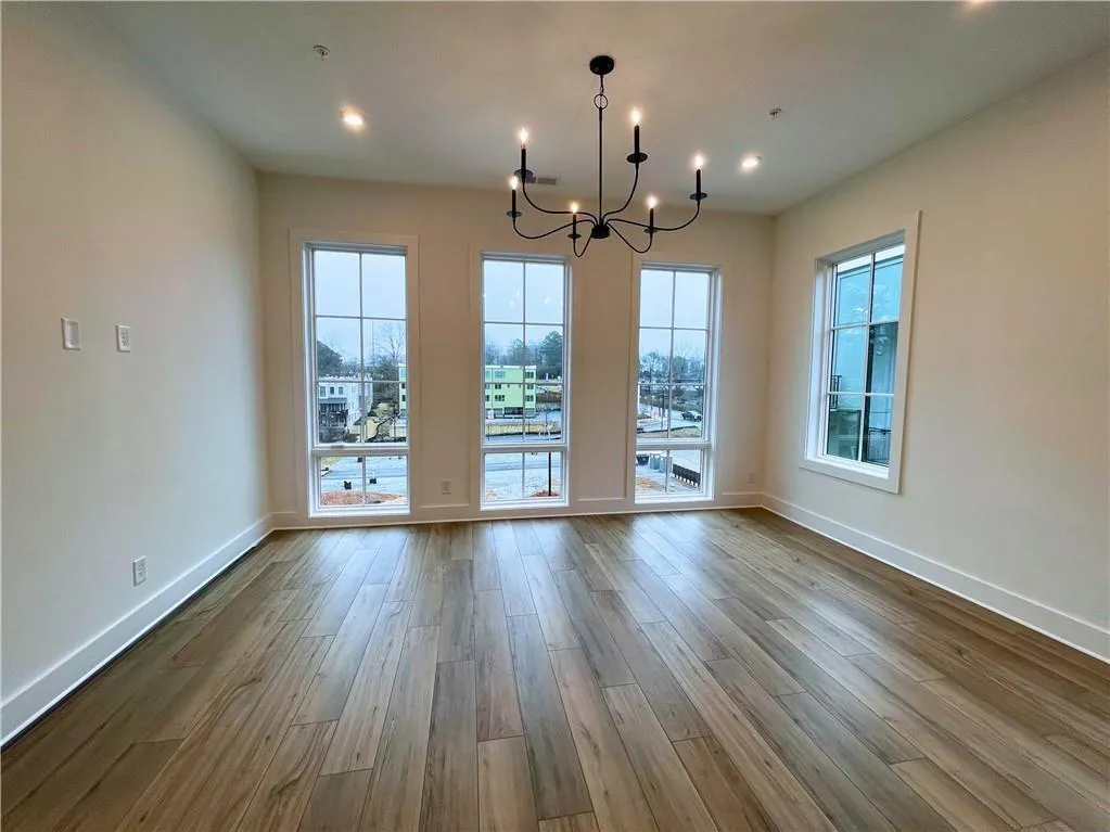 Unfurnished dining area with a chandelier, healthy amount of natural light, and light wood-style flooring