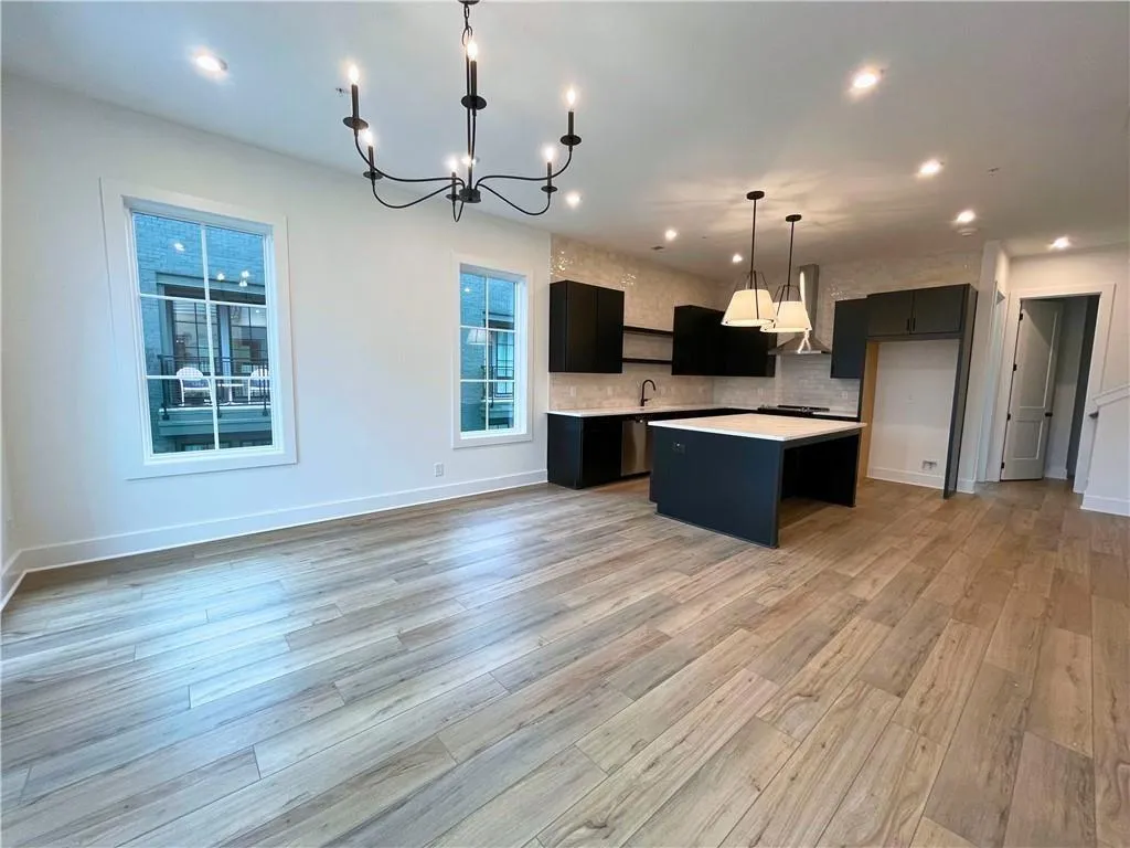 Kitchen with dark cabinets, light countertops, open floor plan, a center island, and suspended lighting