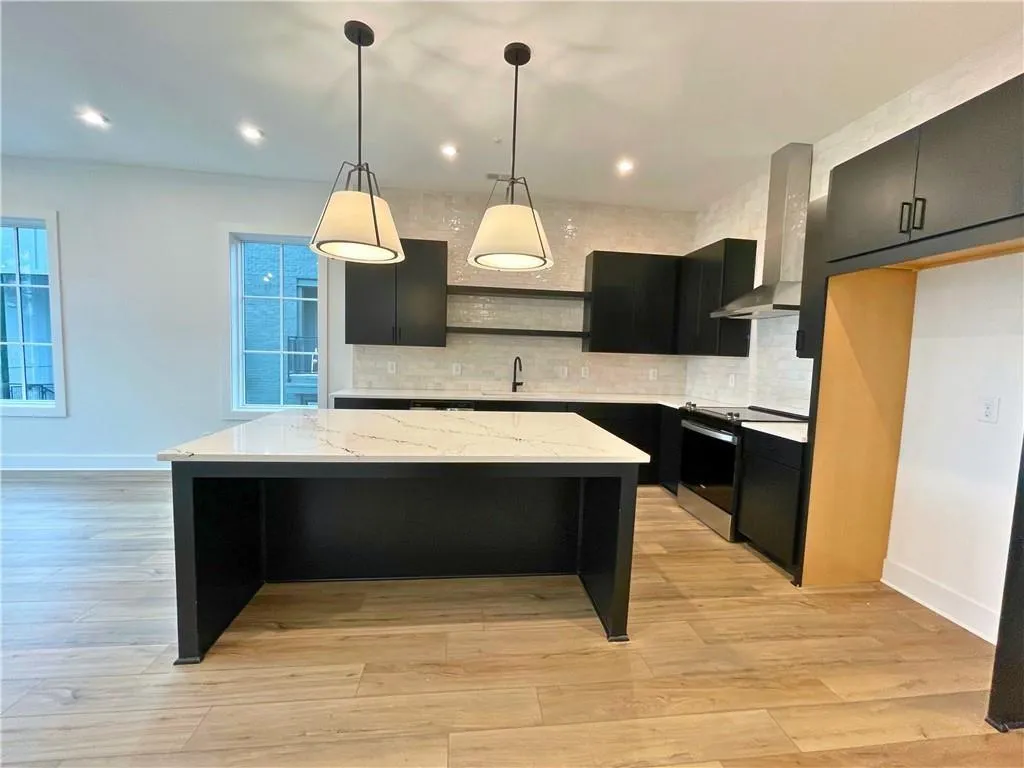 Kitchen with dark cabinets, a kitchen island, decorative light fixtures, and range with electric cooktop