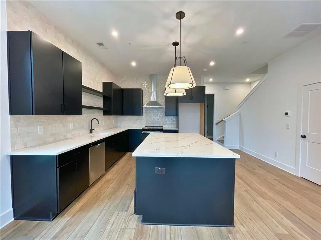 Kitchen featuring dark cabinets, a center island, open shelves, pendant lighting, and light stone countertops
