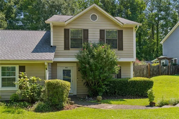 Two-story residence with light-colored siding, dark shutters, and a front entry