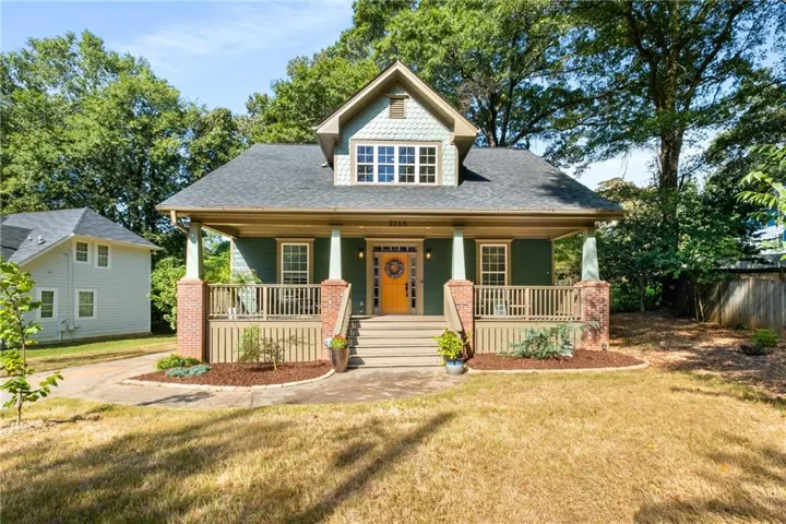 Craftsman-style facade with a covered porch, brick column bases, and a dormer window