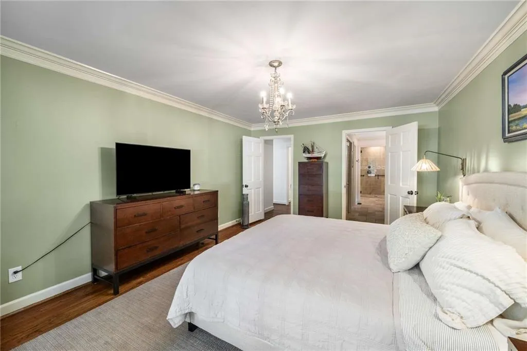 Bedroom on first floor with crown molding, a chandelier, and wood finished floors
