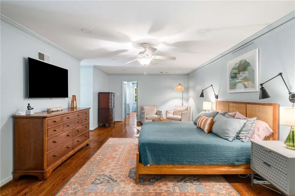 Bedroom with ornamental molding, wood finished floors, and a ceiling fan