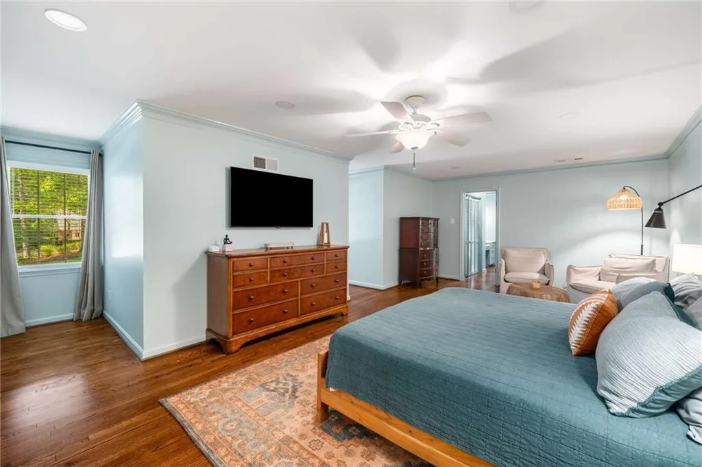 Bedroom with crown molding, wood finished floors, and a ceiling fan