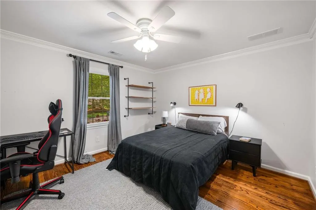 Bedroom with crown molding, wood finished floors, and ceiling fan