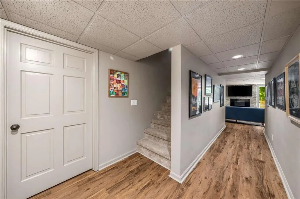 Hallway featuring a paneled ceiling, light wood-type flooring, recessed lighting, and stairway