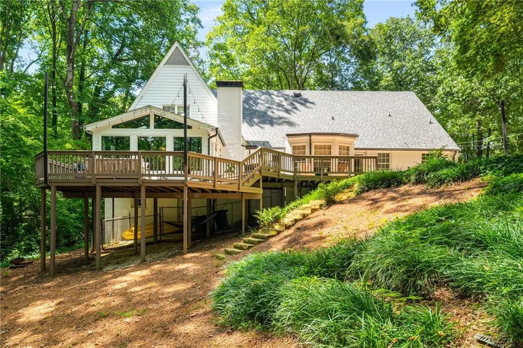 Rear view of house featuring a deck, roof with shingles, and a chimney