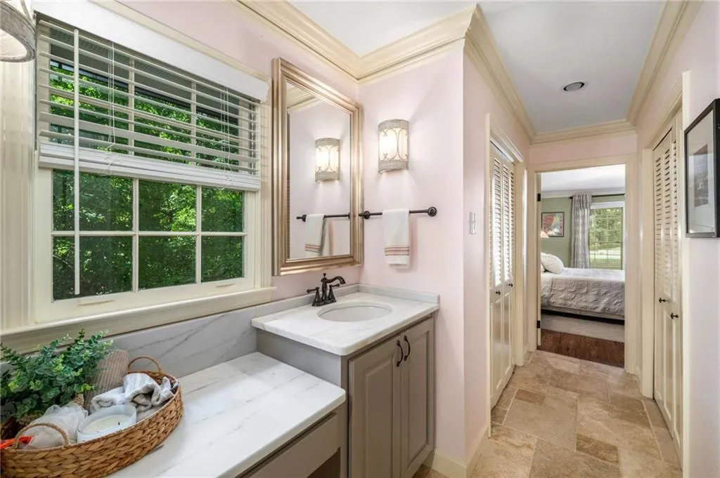 First Foor bathroom featuring stone tile floors, vanity, crown molding, and ensuite bathroom