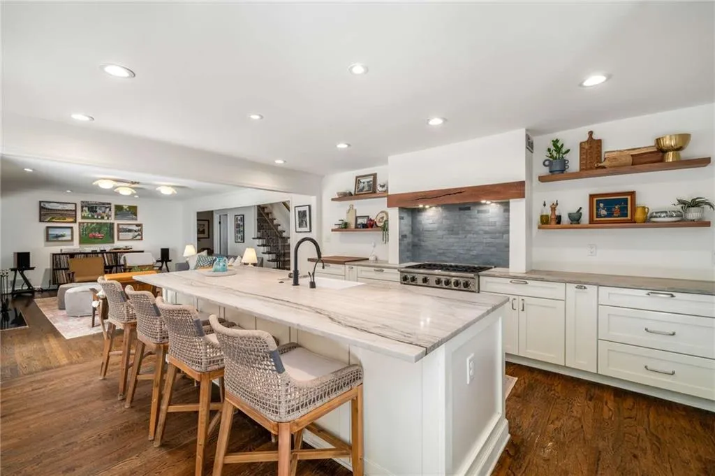 Kitchen with open shelves, light stone countertops, a breakfast bar area, white cabinetry, and dark wood-type flooring