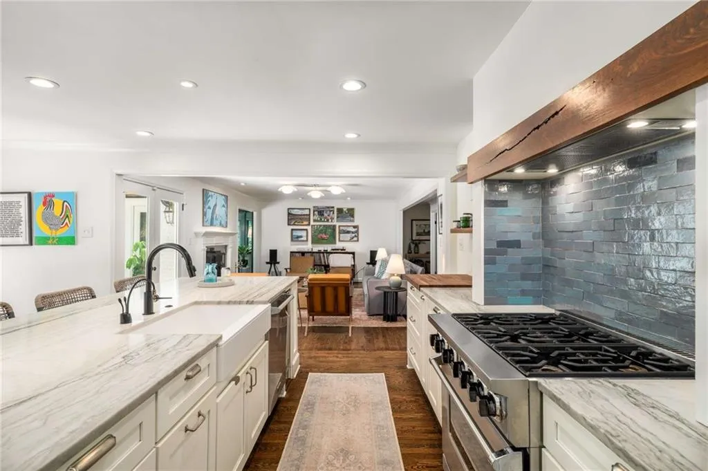 Kitchen with appliances with stainless steel finishes, light stone counters, custom range hood, white cabinetry, and recessed lighting