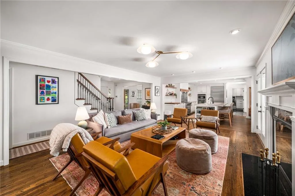 Living area with stairway, dark wood-type flooring, crown molding, a fireplace with flush hearth, and recessed lighting