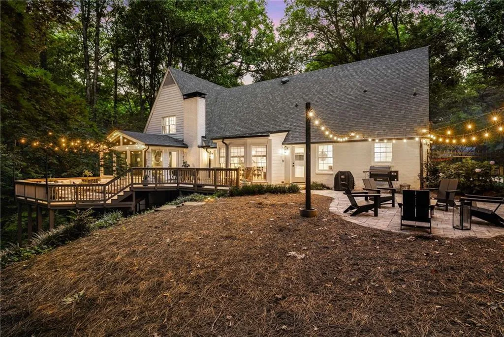 Rear view of house with a patio area, a wooden deck, and roof with shingles