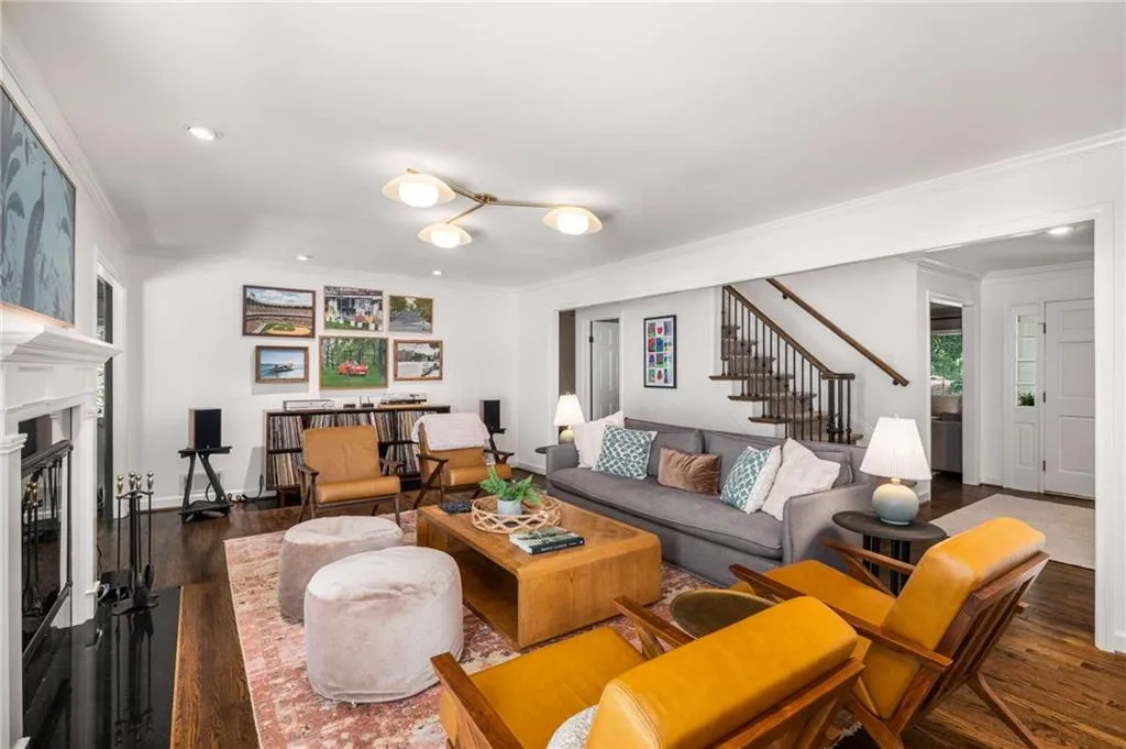 Living area featuring crown molding, wood finished floors, stairs, a fireplace, and recessed lighting