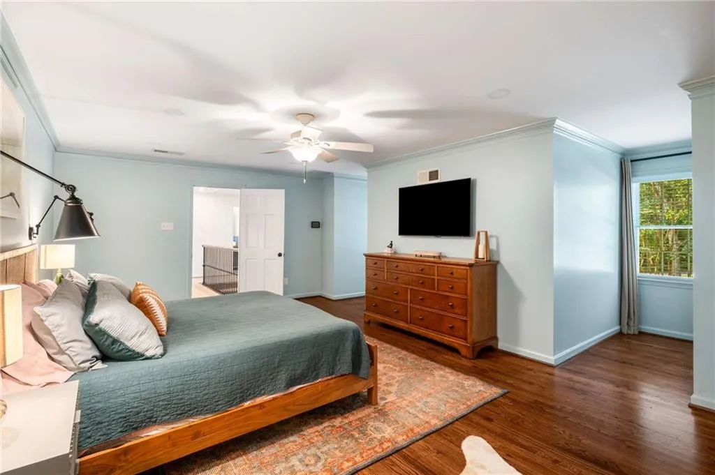 Bedroom with crown molding, wood finished floors, and a ceiling fan