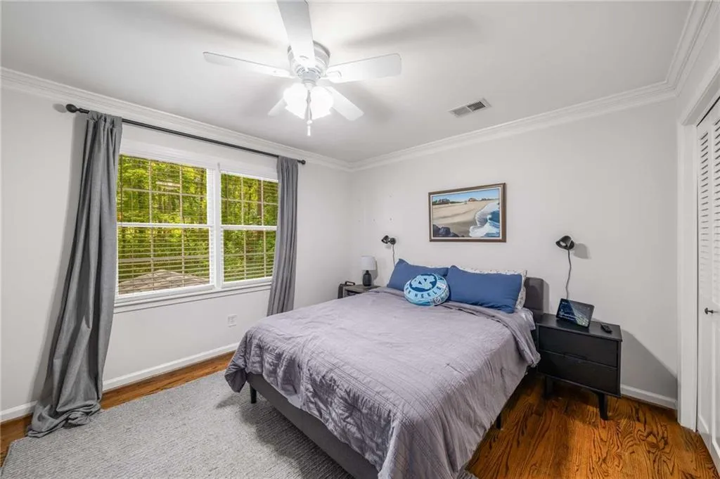 Bedroom featuring crown molding, wood finished floors, a closet, and a ceiling fan