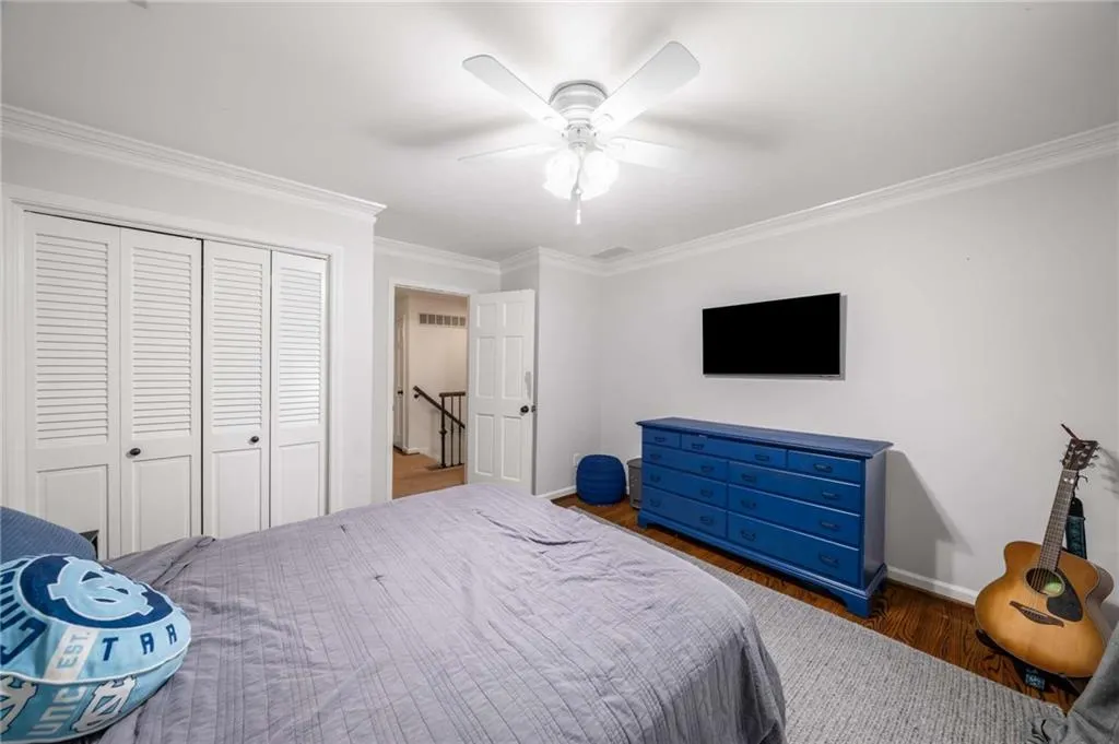 Bedroom with crown molding, wood finished floors, a closet, and ceiling fan