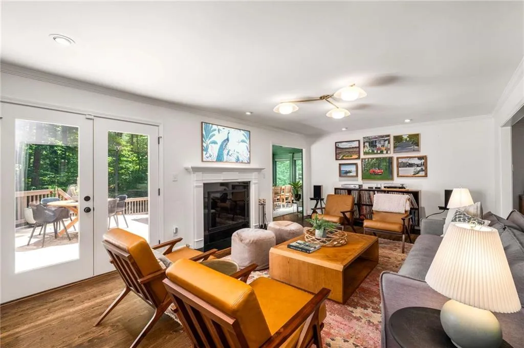 Living area with ornamental molding, french doors, wood finished floors, a glass covered fireplace, and recessed lighting