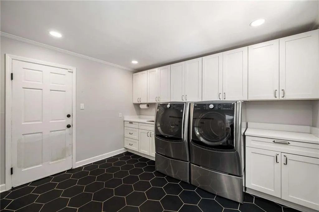 Washroom with cabinet space, ornamental molding, independent washer and dryer, recessed lighting, and dark tile patterned floors