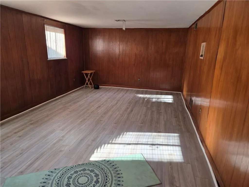 Empty room with light hardwood / wood-style floors and wooden walls