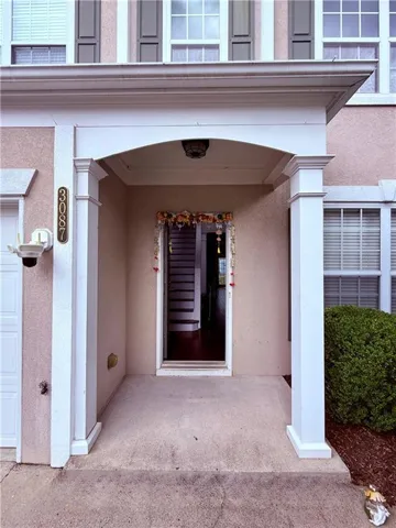 Portico entrance with decorative columns and an overhead light fixture