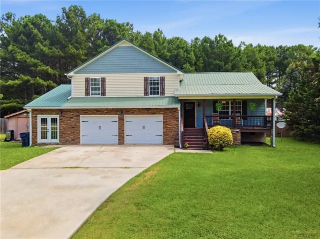 Two-story residence featuring a green metal roof, brick and siding exterior, and a covered front porch