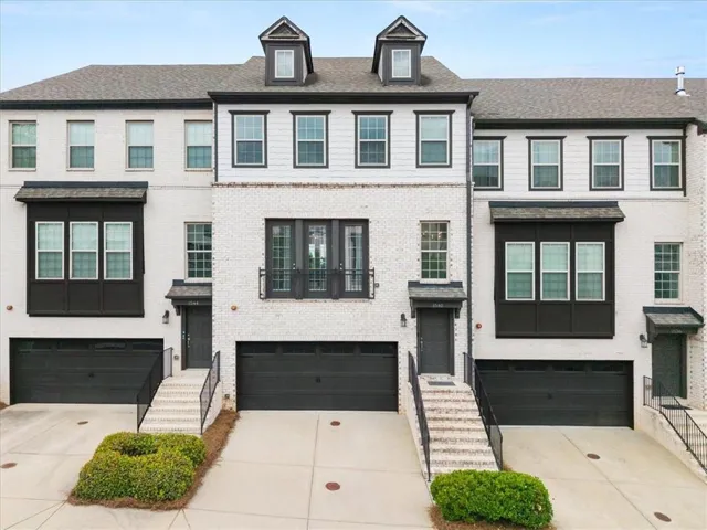 Modern townhome exterior featuring light-colored brick and dark trim