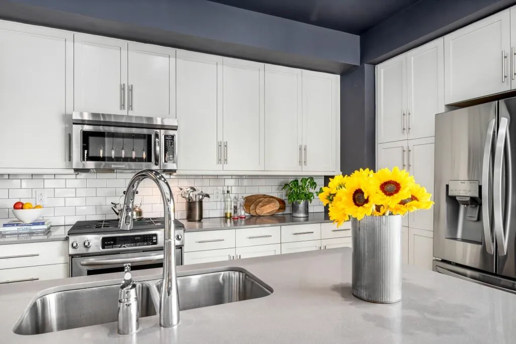 Enjoy quartz countertops, a large center island with breakfast bar seating, timeless subway tile backsplash, premium stainless-steel appliances including a gas range, and classic slim shaker cabinetry with abundant storage.