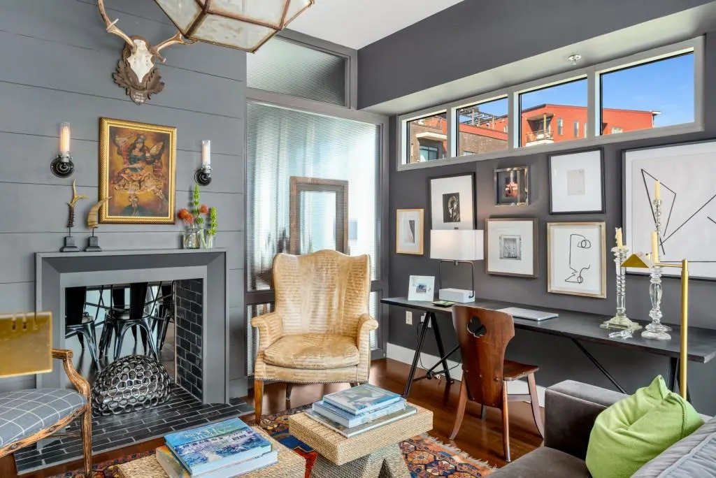 Dramatic tall ceilings and floor-to-ceiling windows create an airy atmosphere, while the living area features a striking, decorative fireplace with shiplap surround.