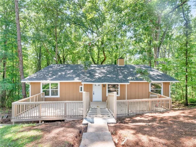Exterior featuring a spacious wood deck, wood siding, and multiple windows