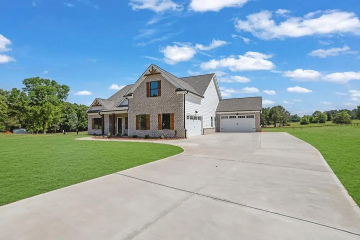 Brick and siding exterior featuring gabled rooflines, multiple garage bays, and a concrete driveway