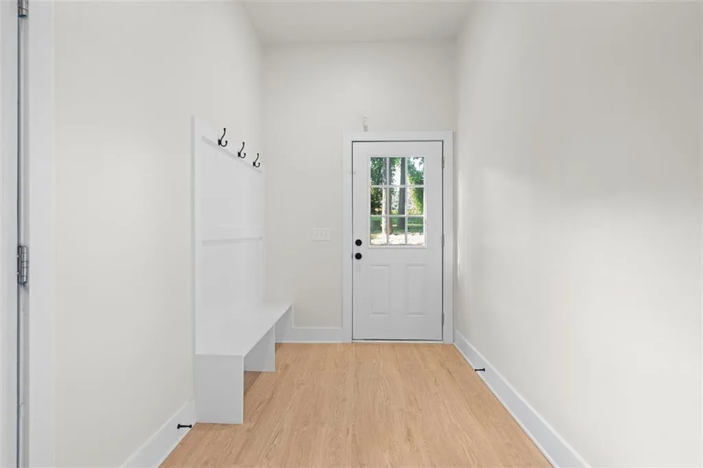 Mudroom featuring light wood-style flooring and baseboards