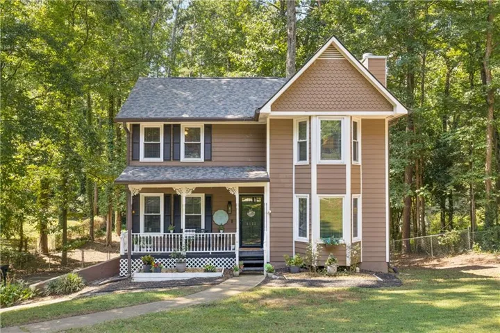 Two-story residence featuring a covered front porch, white window trim, and a prominent bay window structure