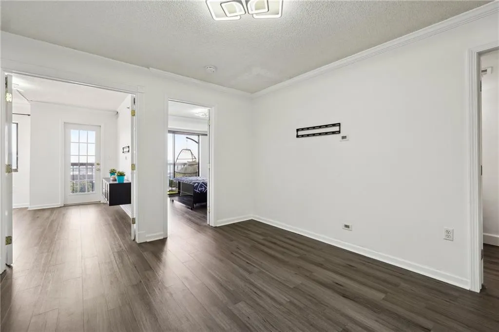 Spare room with dark hardwood / wood-style floors, crown molding, and a textured ceiling