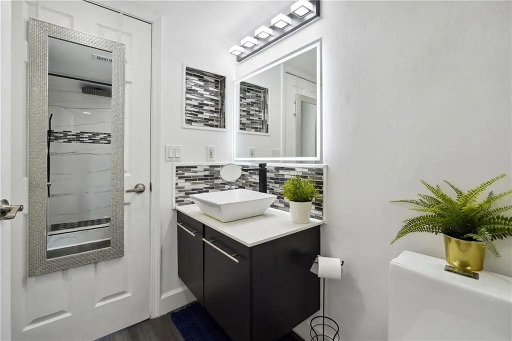Bathroom with backsplash, wood-type flooring, and vanity with extensive cabinet space