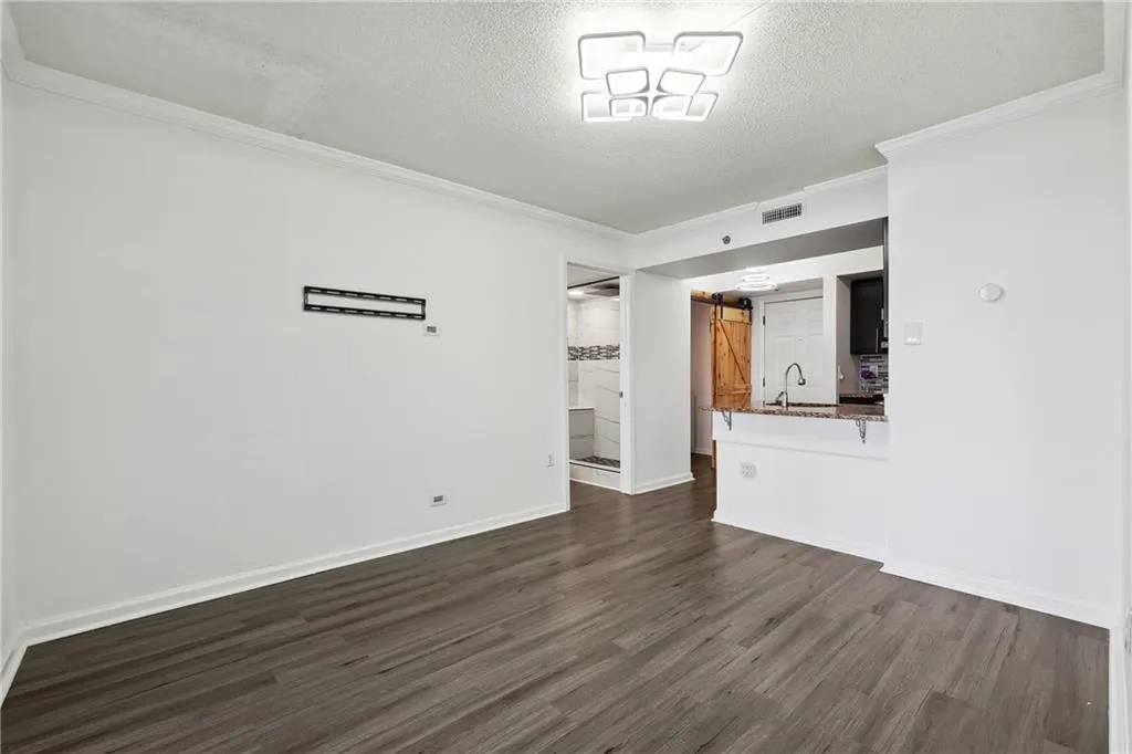 Unfurnished room with sink, a barn door, dark hardwood / wood-style floors, and a textured ceiling