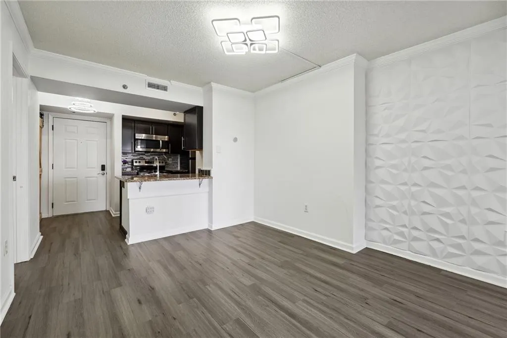 Empty room featuring ornamental molding, dark wood-type flooring, and a textured ceiling