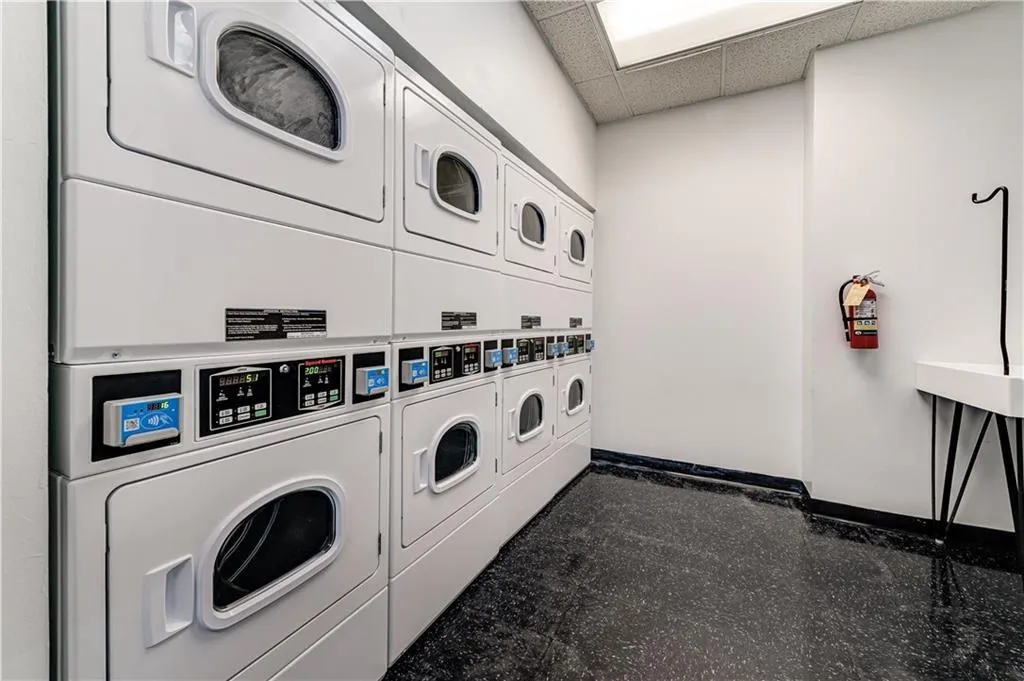 Laundry room featuring stacked washer and clothes dryer, washer and dryer, and tile floors