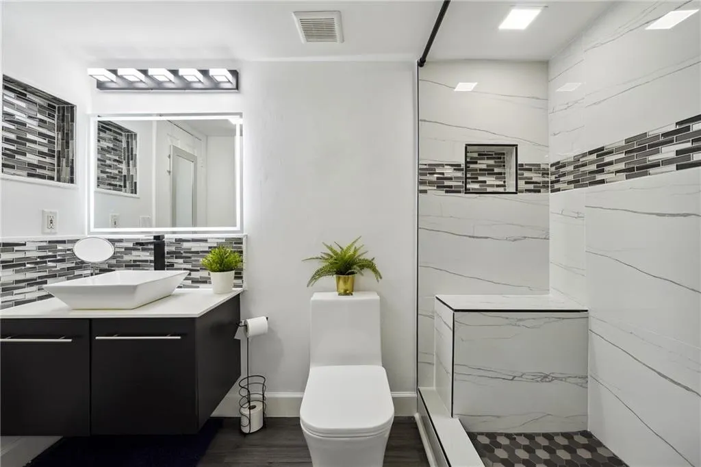 Bathroom with tasteful backsplash, hardwood / wood-style floors, toilet, a shower with shower door, and vanity